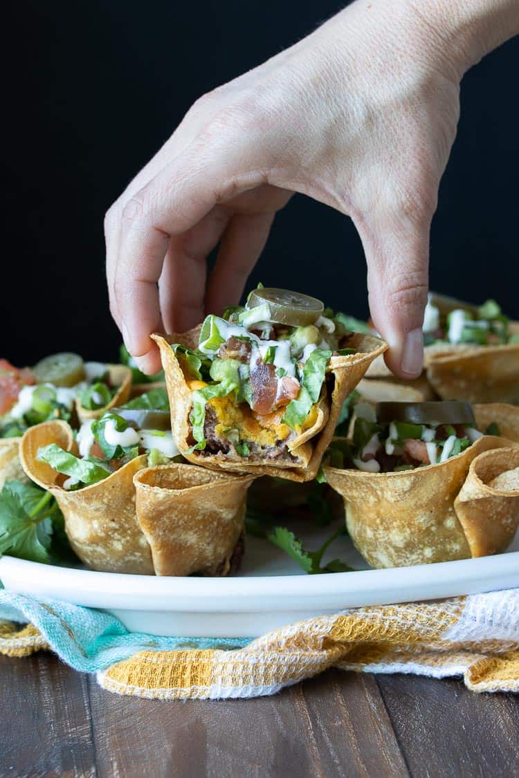 Hand picking up a half eaten crunchy taco cup with filling showing