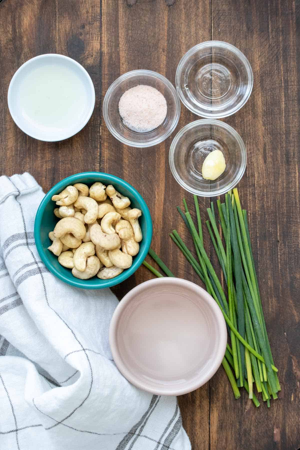 Bowls filled with ingredients to make a creamy cashew based chive sauce