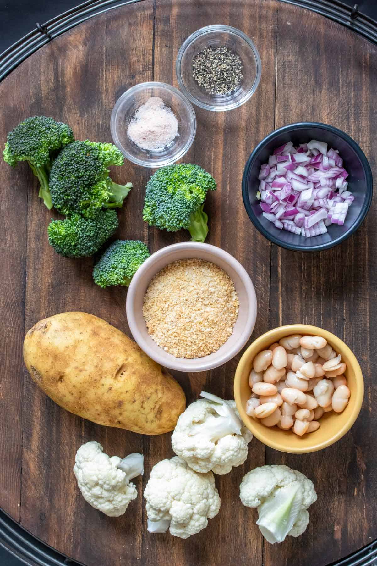 Table topped with veggies, breadcrumbs, beans, salt and pepper.