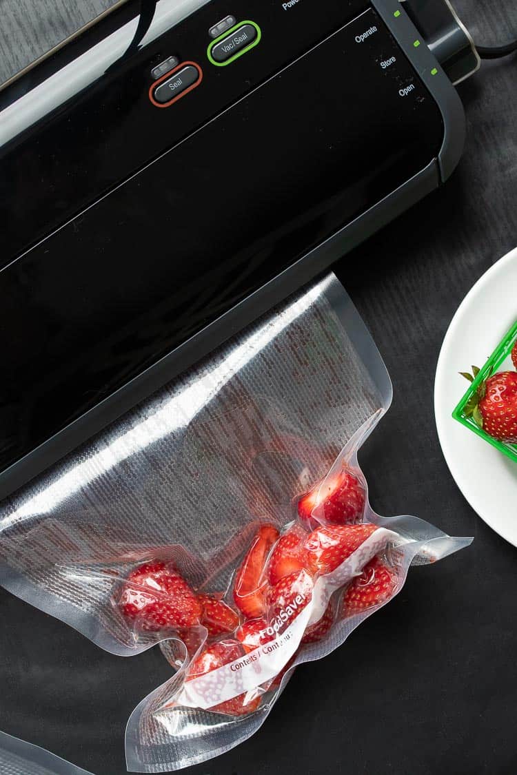 Fresh strawberries being sealed in a vacuum seal bag by a Foodsaver machine