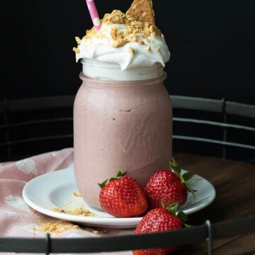 Pink smoothie in a glass jar with whipped cream and graham crackers