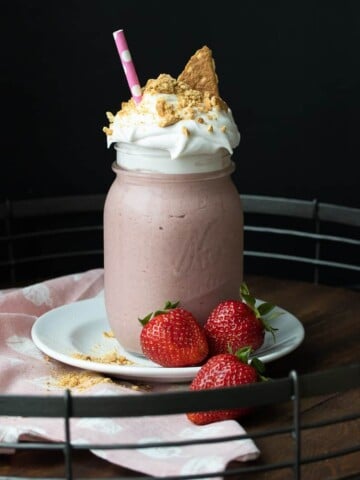 Pink smoothie in a glass jar with whipped cream and graham crackers