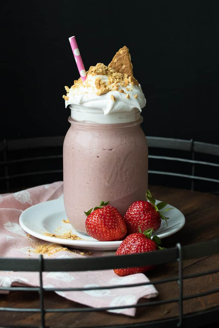 Pink smoothie in a glass jar with whipped cream and graham crackers 