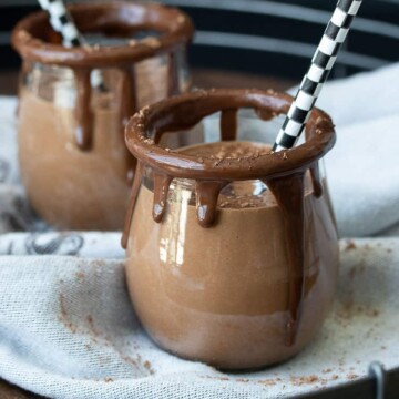 Glass jars rimmed with melted chocolate filled with a chocolate smoothie