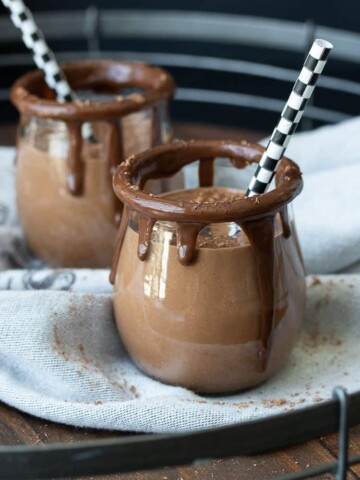 Glass jars rimmed with melted chocolate filled with a chocolate smoothie