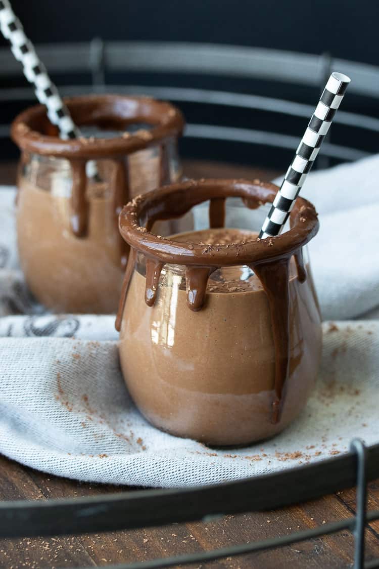 Glass jars rimmed with melted chocolate filled with a chocolate smoothie