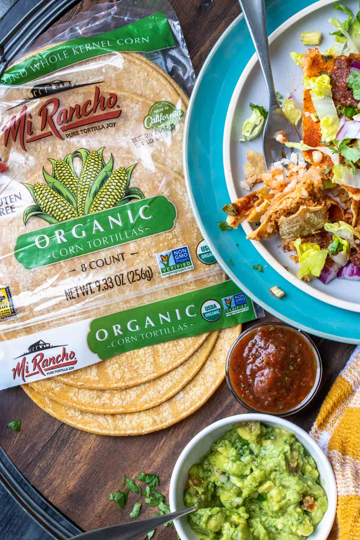 Top view of a package of corn tortillas next to a plate of enchiladas