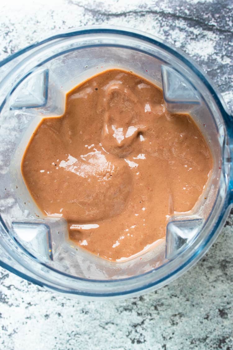 Top view of a blender with a red orange smoothie in it