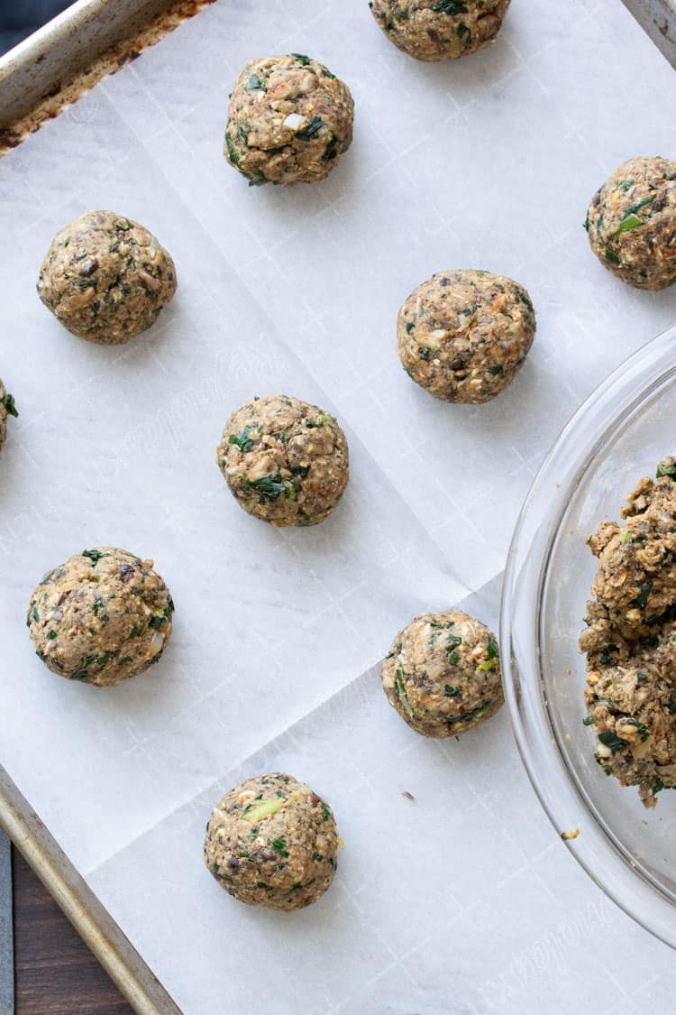 Cookie sheet with parchment paper and bean based vegan meatballs