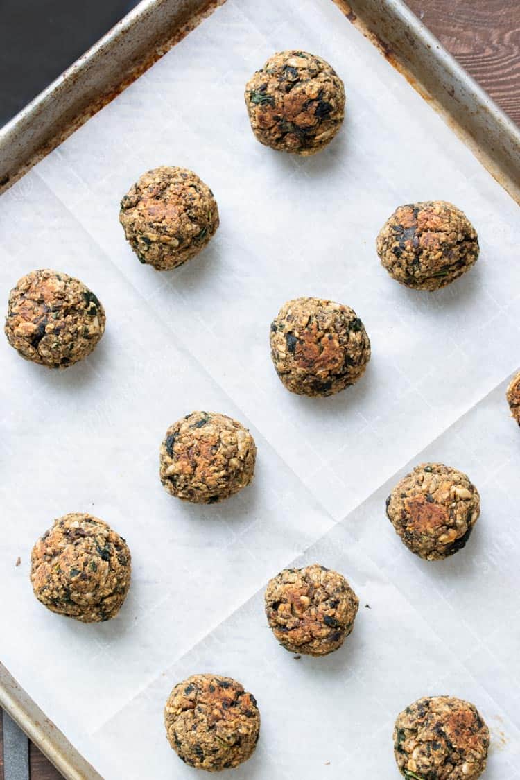 Baked vegan meatballs on a parchment lined cookie sheet