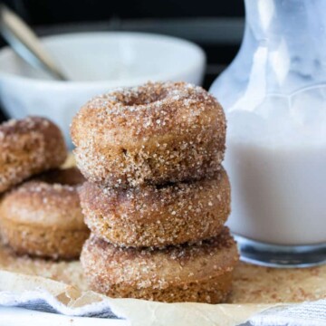 Stack of three cinnamon sugar donuts on a white plate