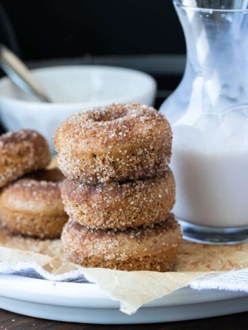 Stack of three cinnamon sugar donuts on a white plate