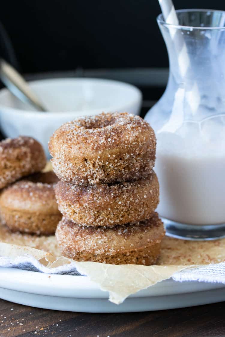 Stack of three cinnamon sugar donuts on a white plate