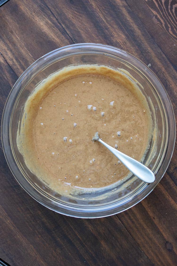 Glass bowl with brown donut batter and a spoon