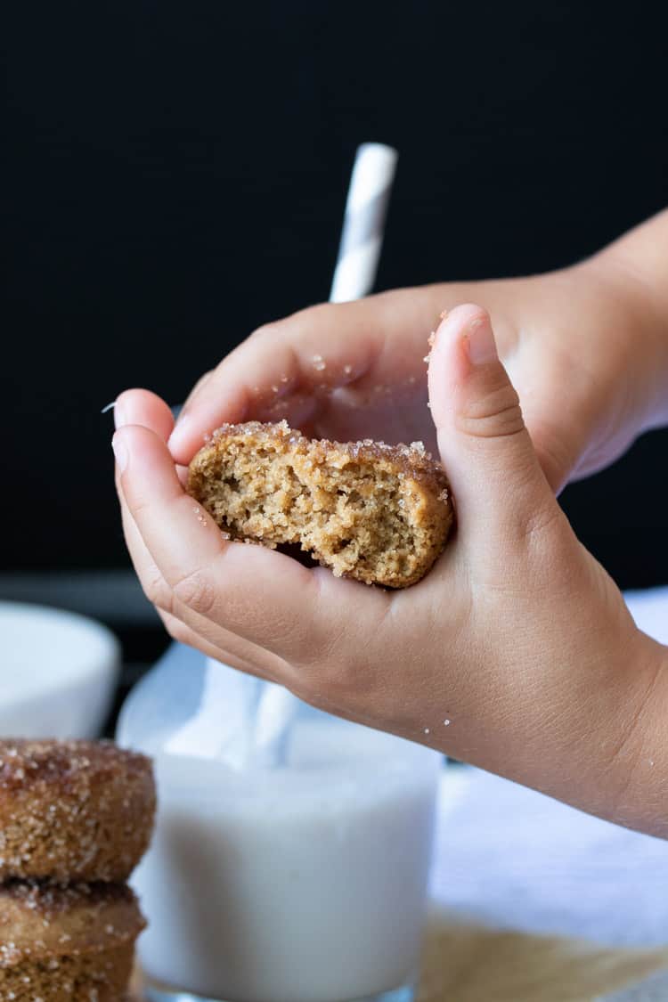Child's hands holding a half eaten cinnamon sugar donut