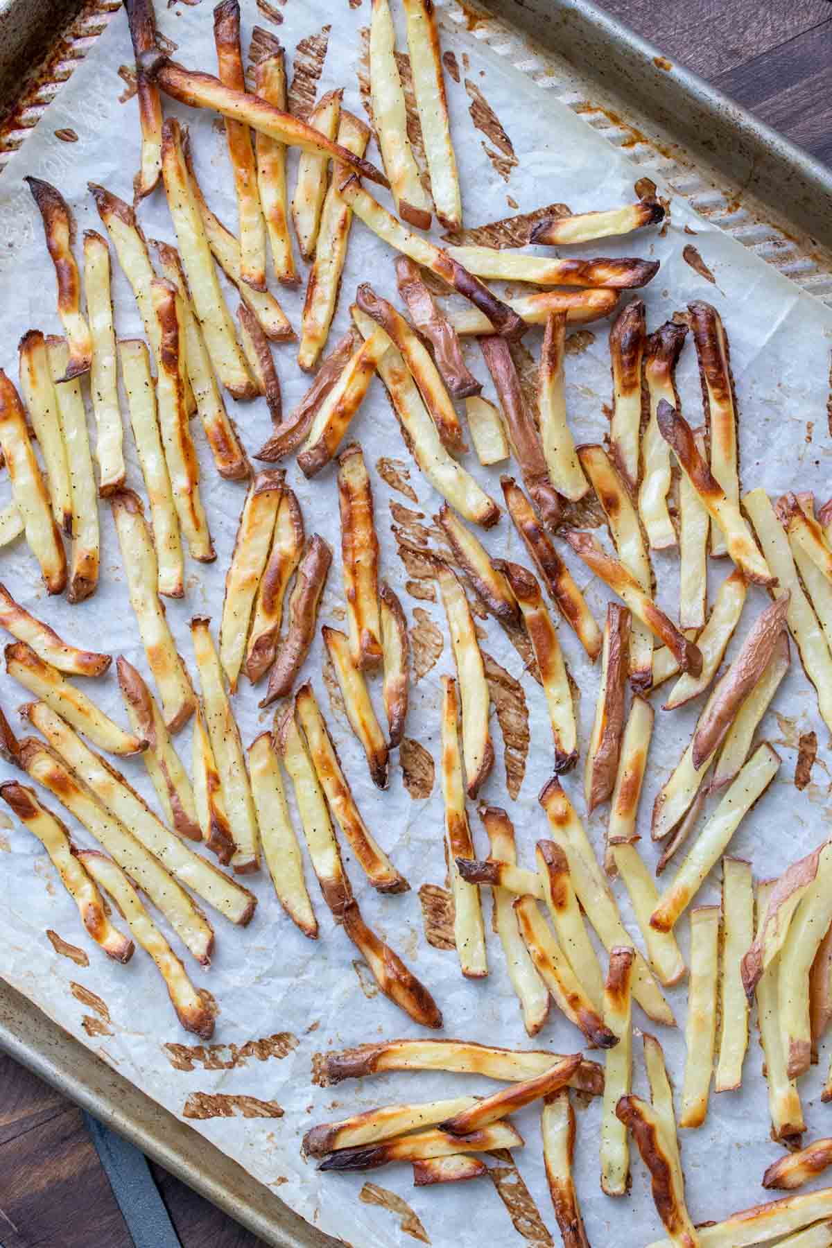 Crispy baked french fries on a parchment lined cookie sheet.