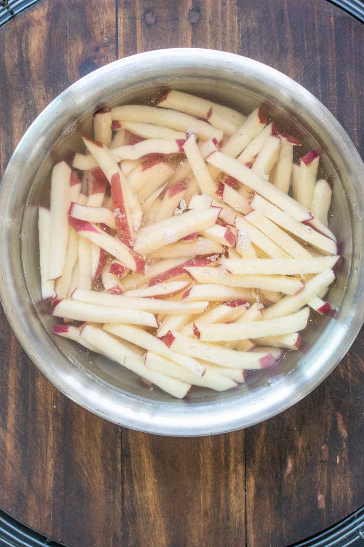 Raw french fries soaking in a bowl of water