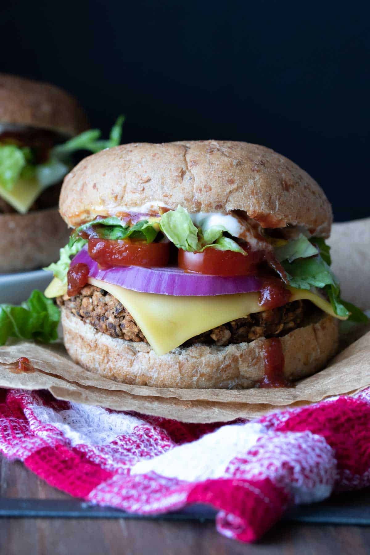 A veggie burger on a bun topped with cheese, red onion, tomato and lettuce