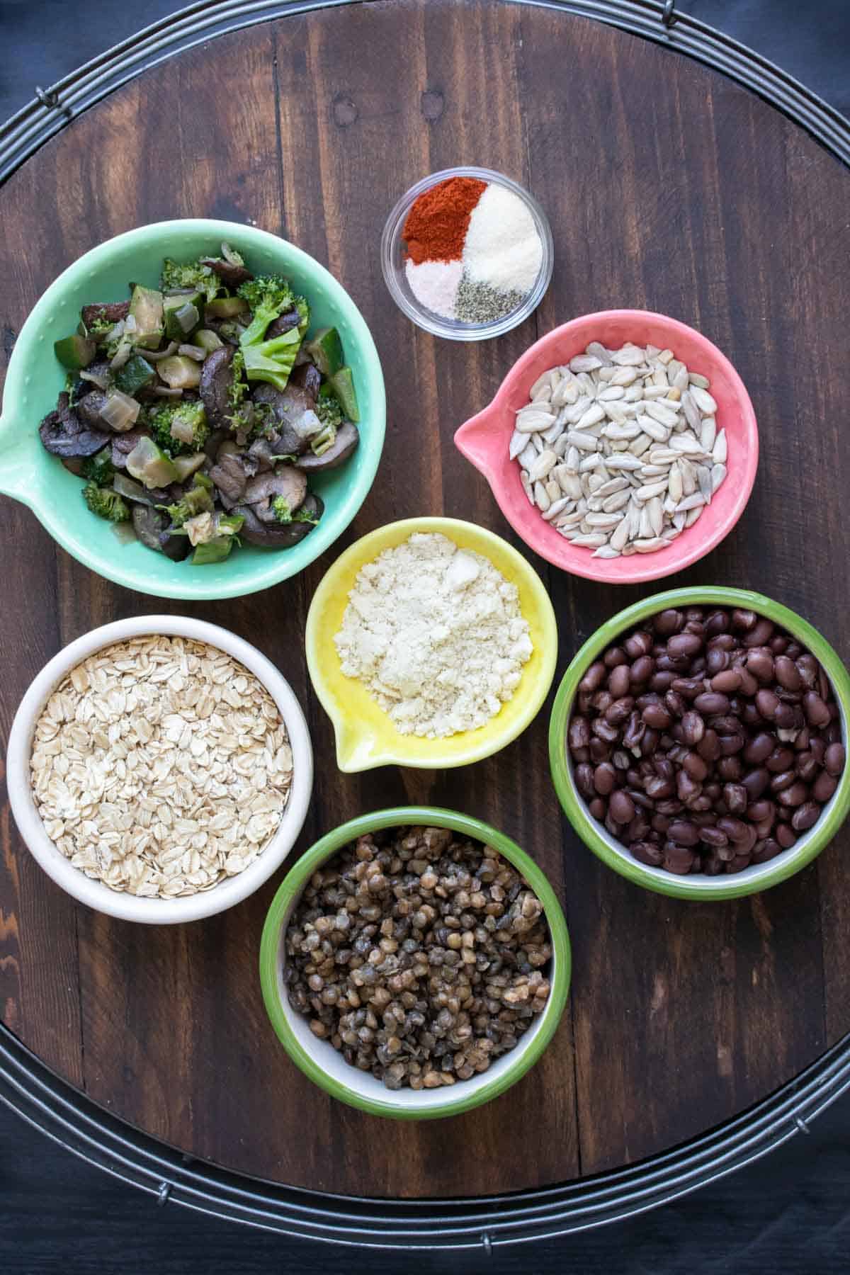 Veggie burger ingredients in colorful bowls on a wooden table