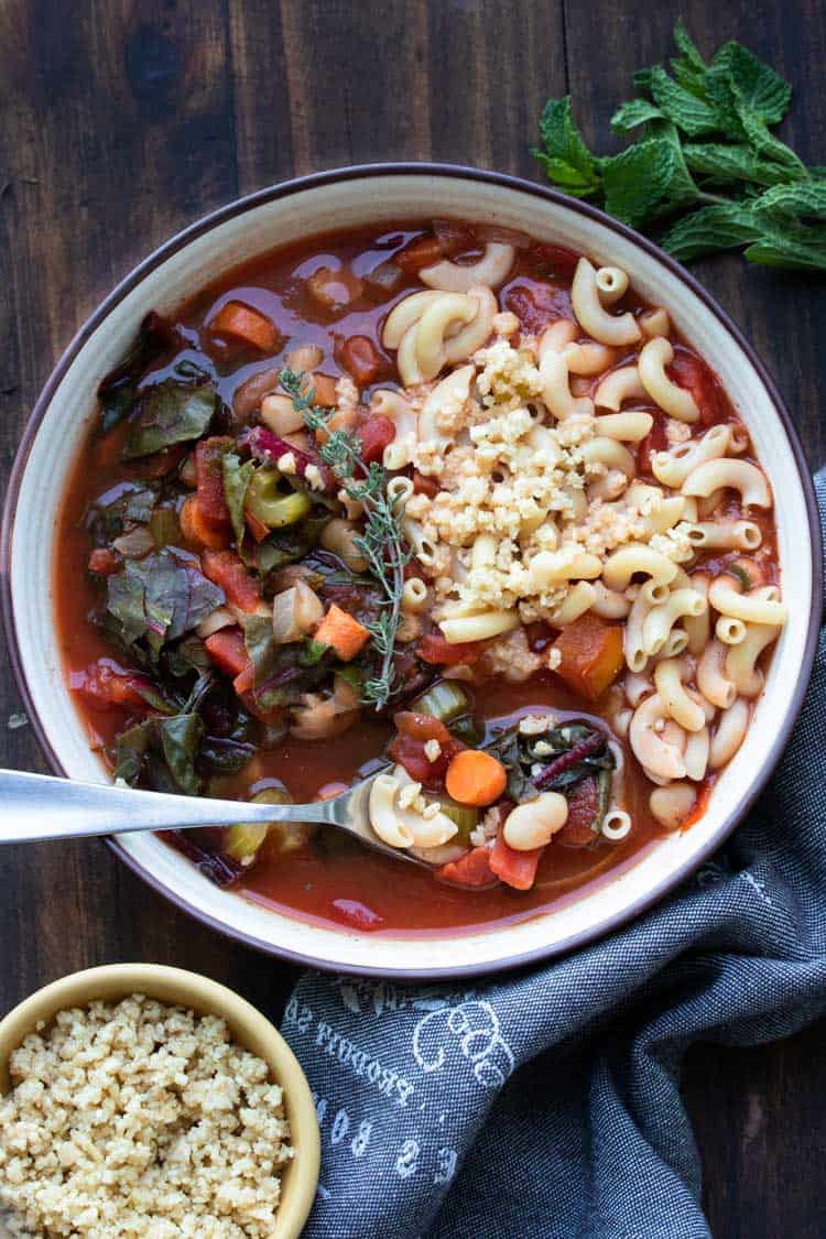 Spoon taking a bite out of a bowl of vegetable minestrone soup