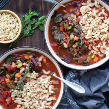 Two bowls of vegetable minestrone soup on a wooden tray