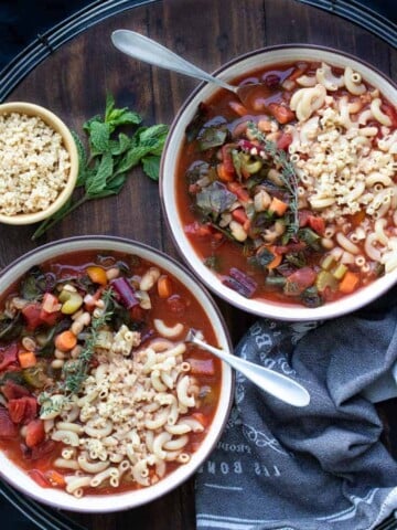 Two bowls of vegetable minestrone soup on a wooden tray