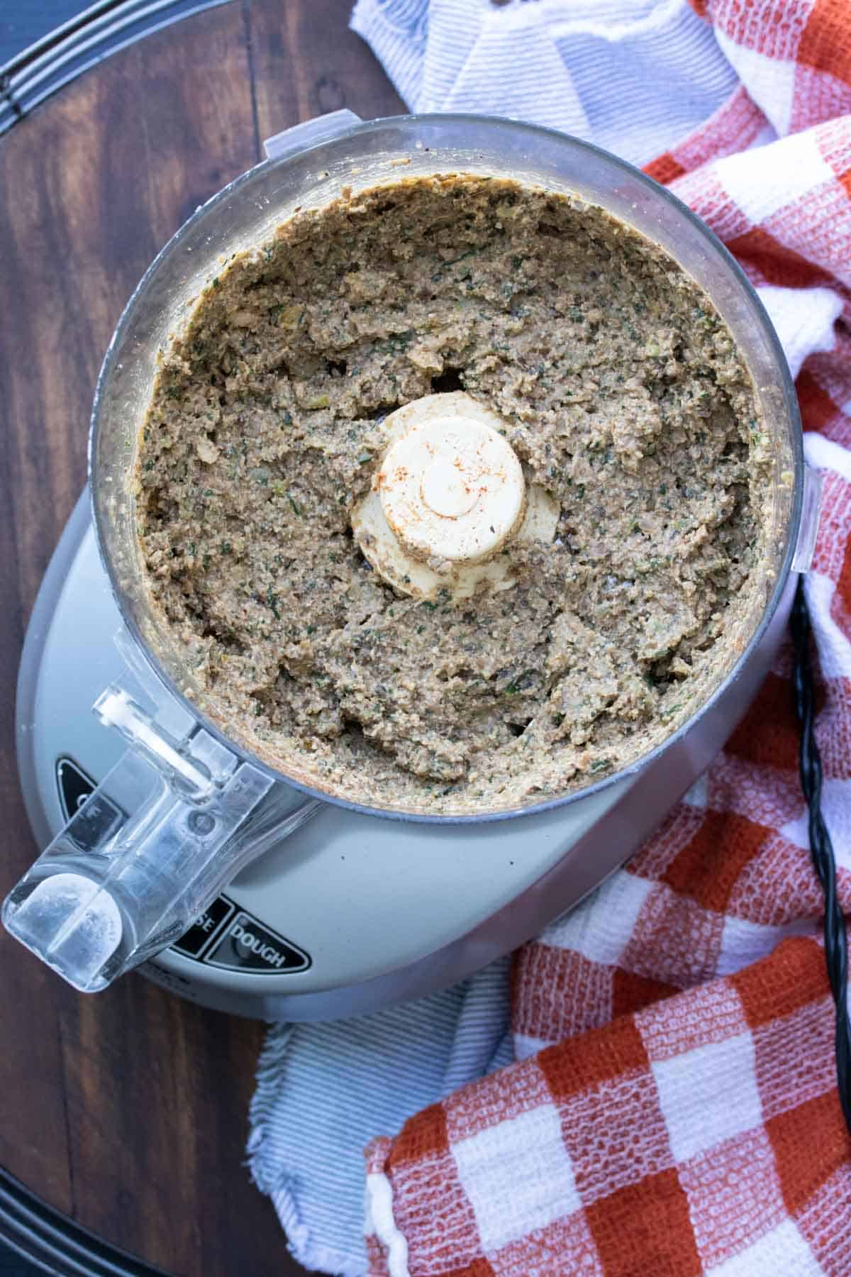 Top view of a food processor filled with bean and veggie taquito filling