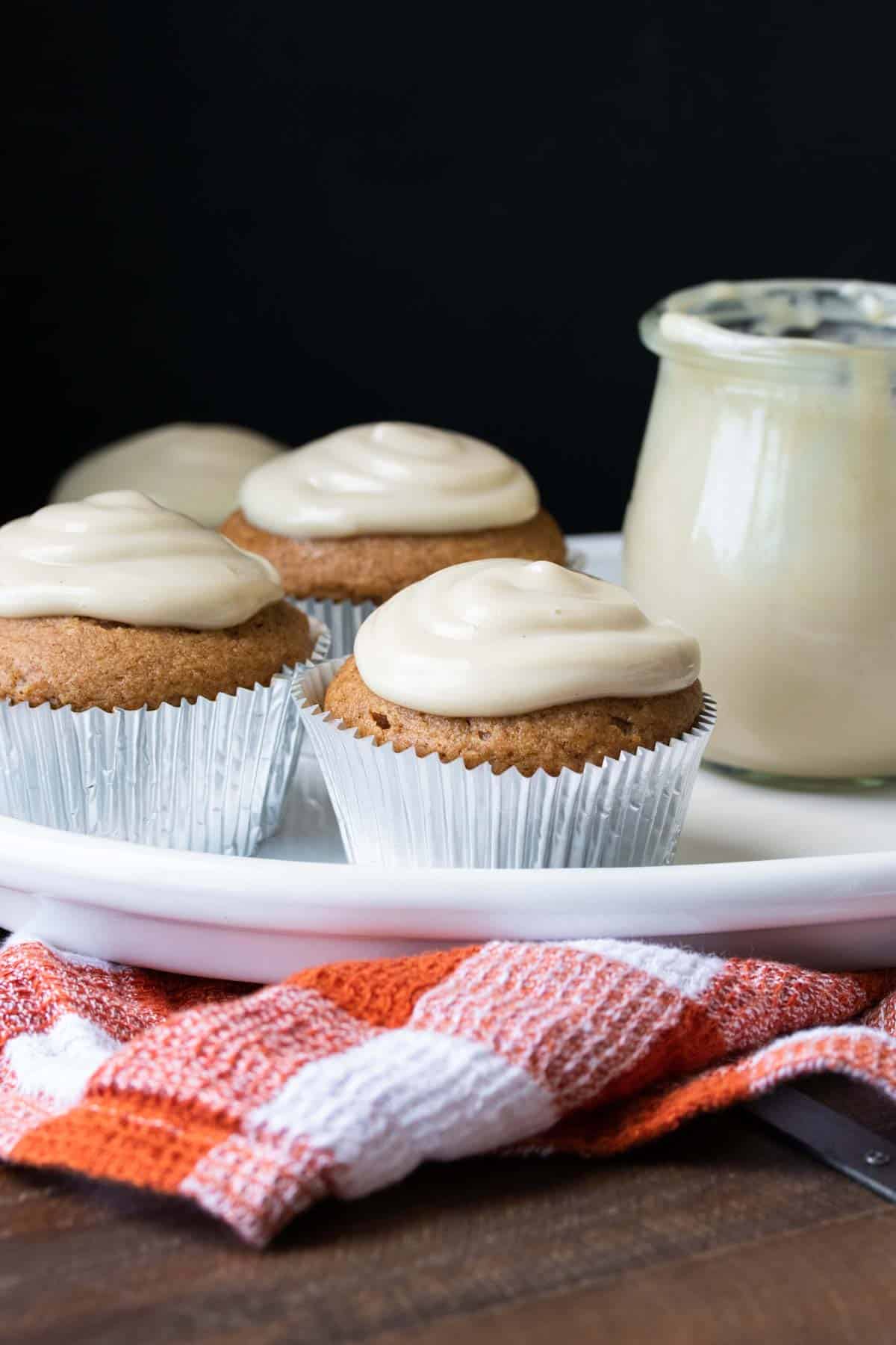 Pumpkin cupcakes with white frosting on a white plate