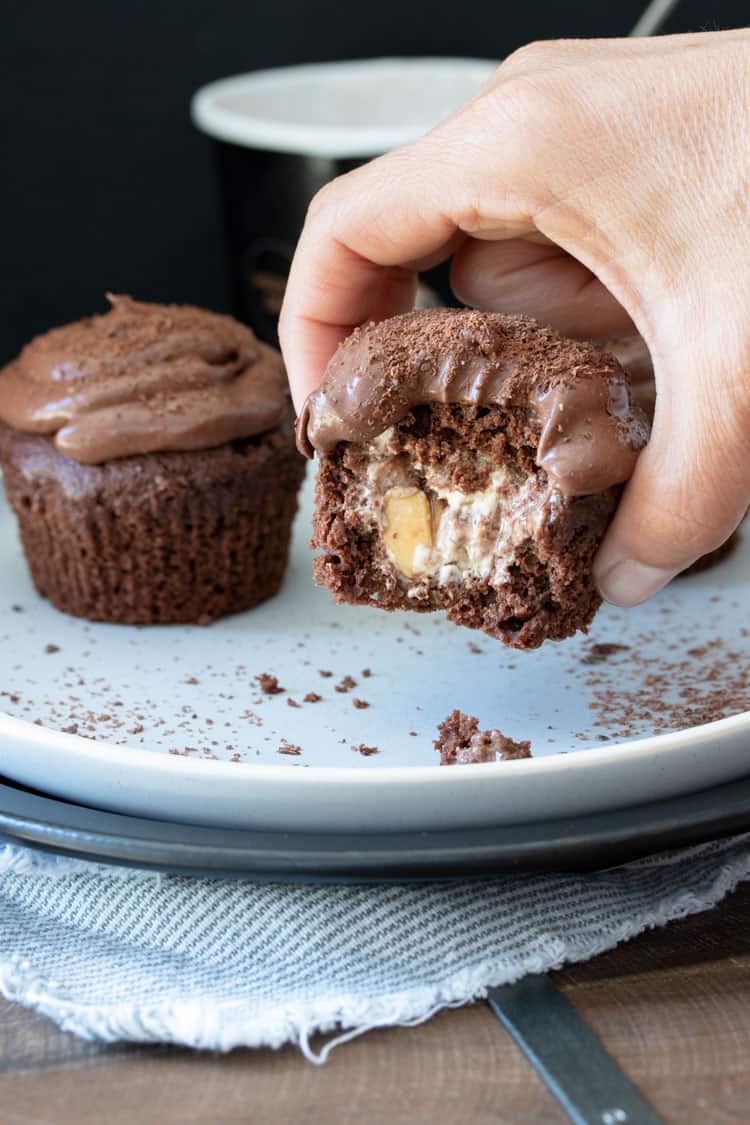 Hand grabbing chocolate cupcakes stuffed with vanilla ice cream