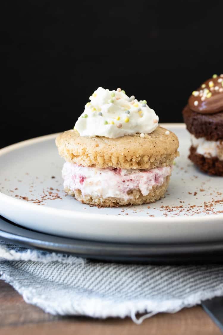 Layered strawberry ice cream and vanilla cupcake topped with whipped cream and sprinkles