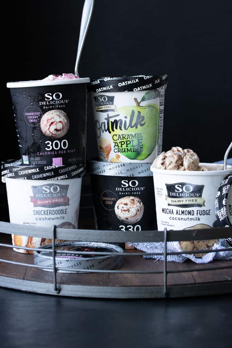 Cartons of ice cream piled on top of each other on a wooden tray