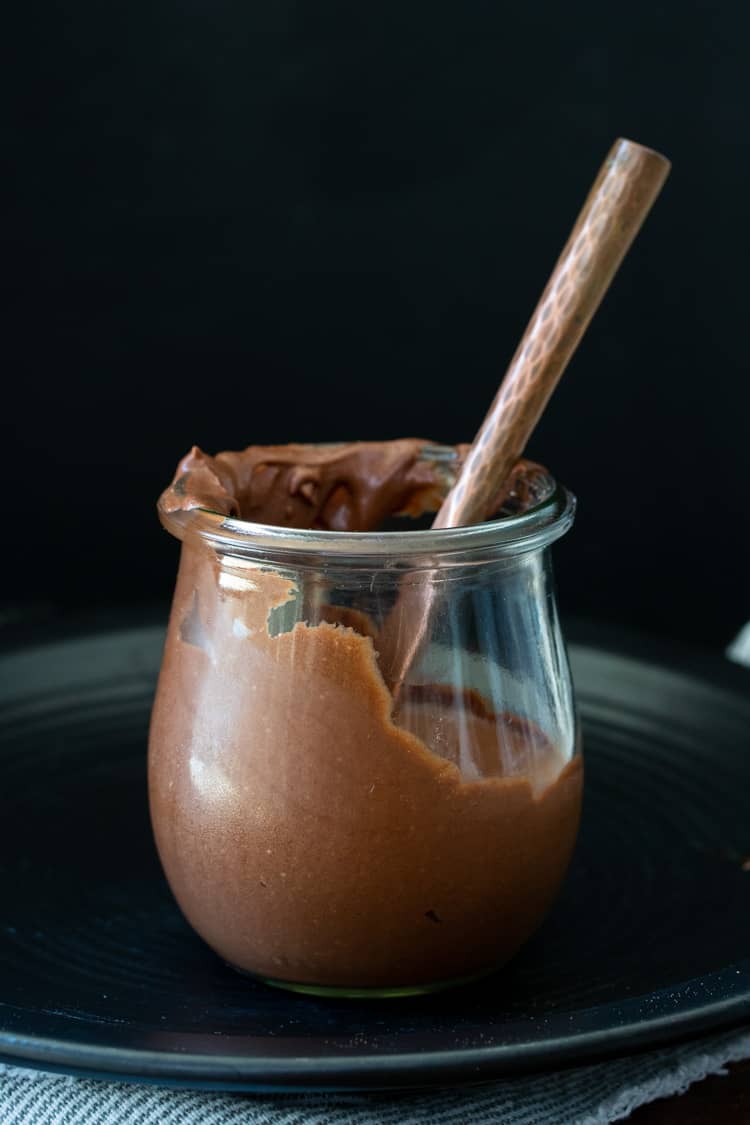 A knife in a glass jar filled with chocolate frosting