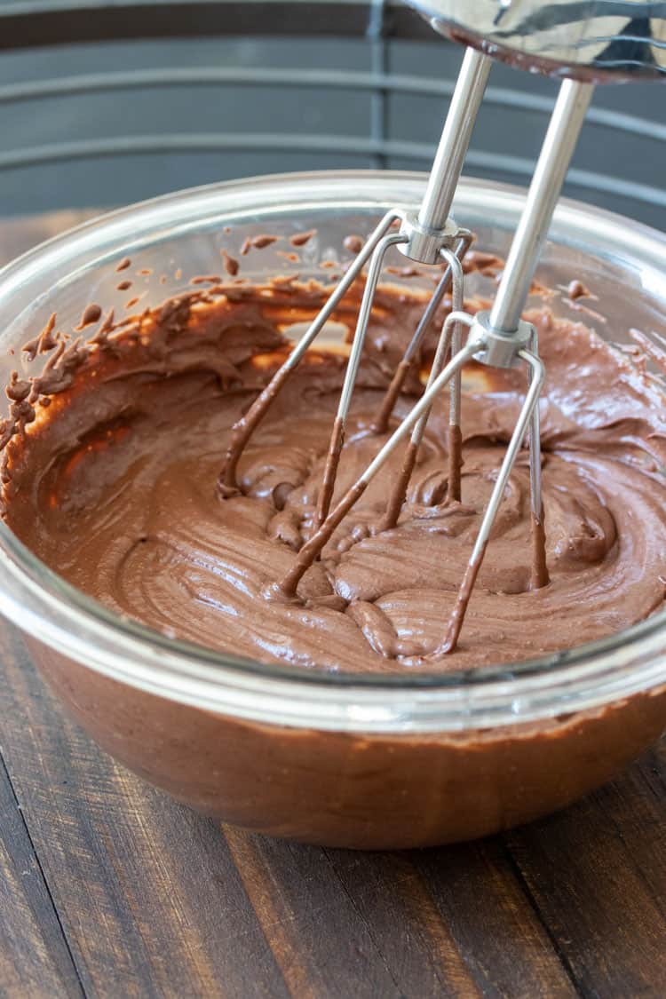 Smooth chocolate frosting whipping up in a glass bowl