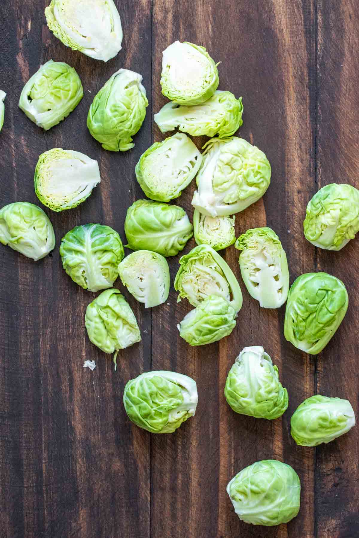 Cleaned and cut in half Brussels sprouts on a wooden table.