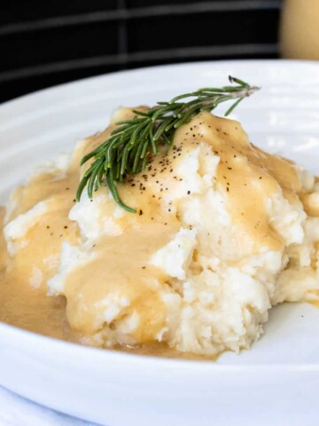 Rosemary sprig on a pile of mashed potatoes covered in gravy