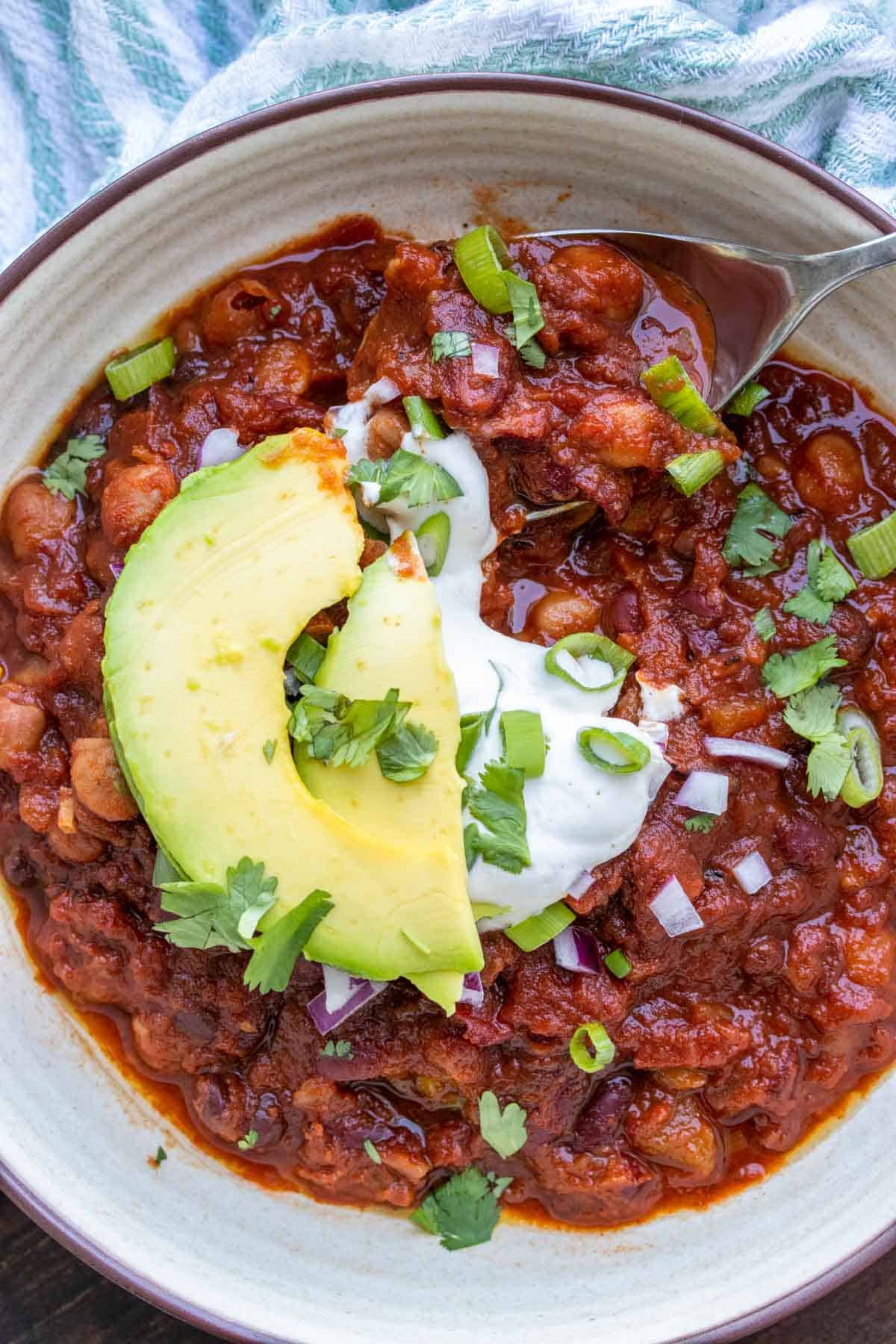 Spoon getting a bite of bean chili from a tan bowl