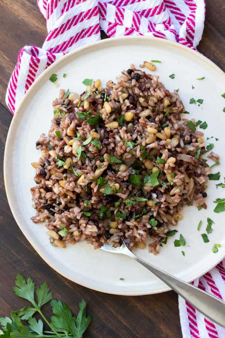 White plate with rice stuffing on it covered with chopped parsley.