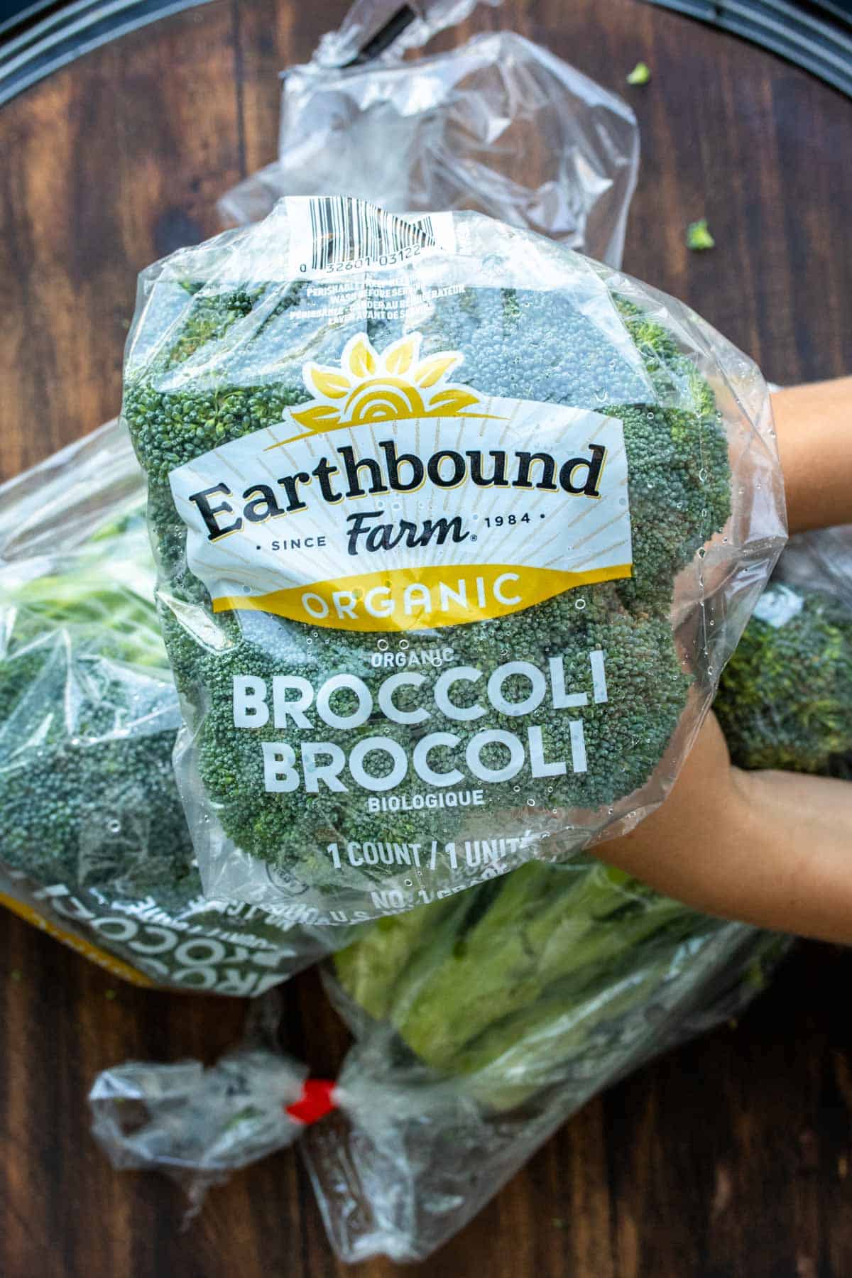 Hands holding a stalk of Earthbound Farm Organic brand of broccoli