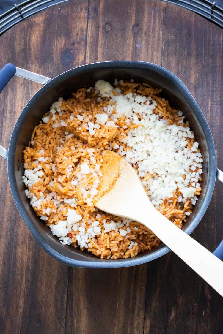 Mexican rice with riced cauliflower being mixed in a pot