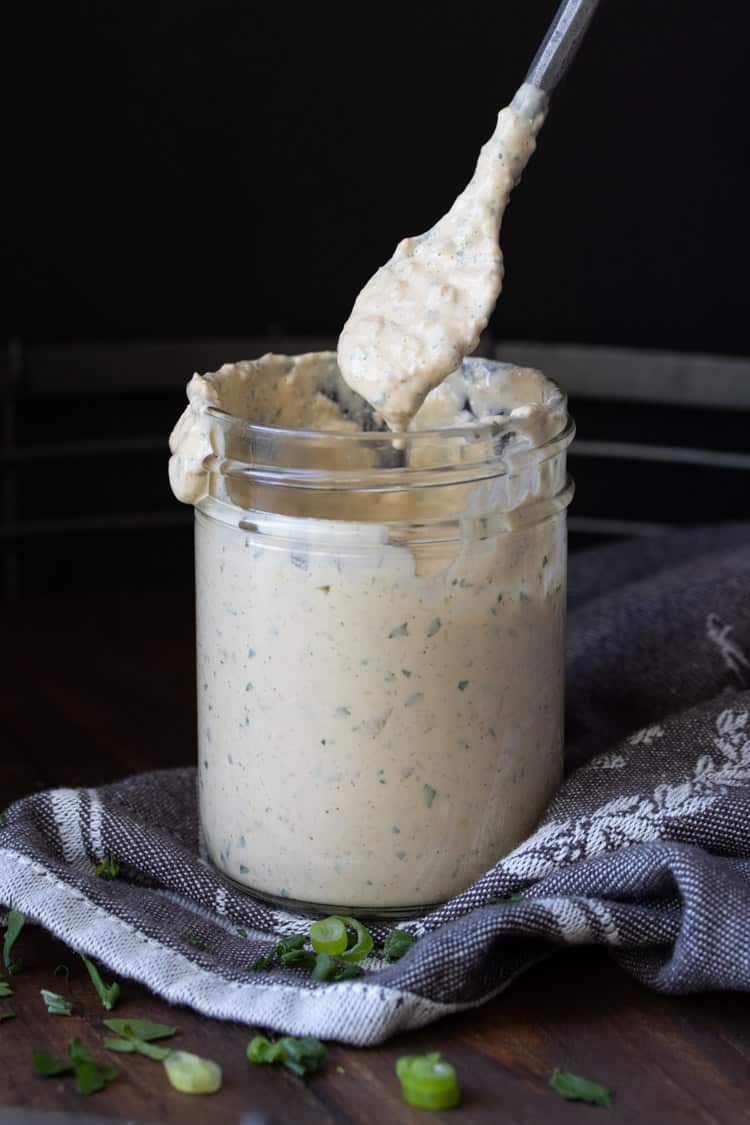 Spoon dipping into a glass jar of remoulade sauce