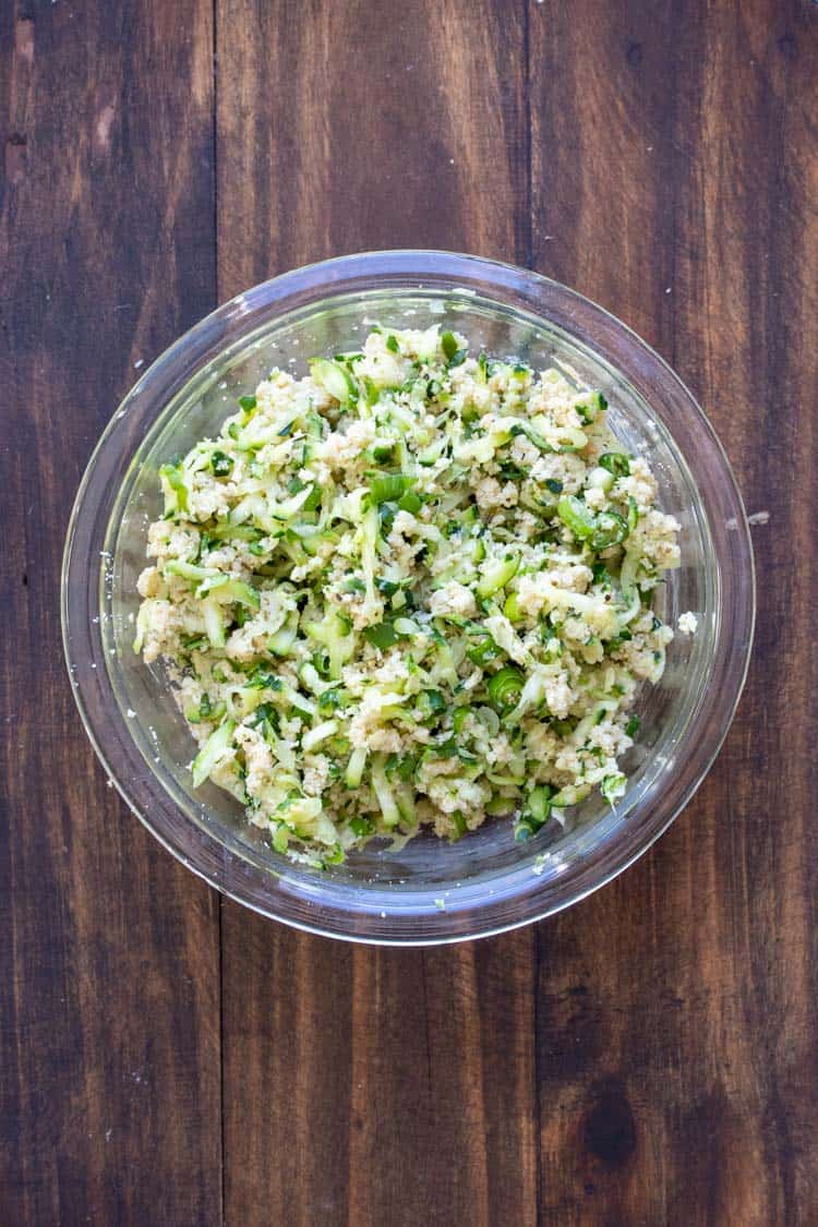 Glass bowl filled with raw zucchini fritter mixture