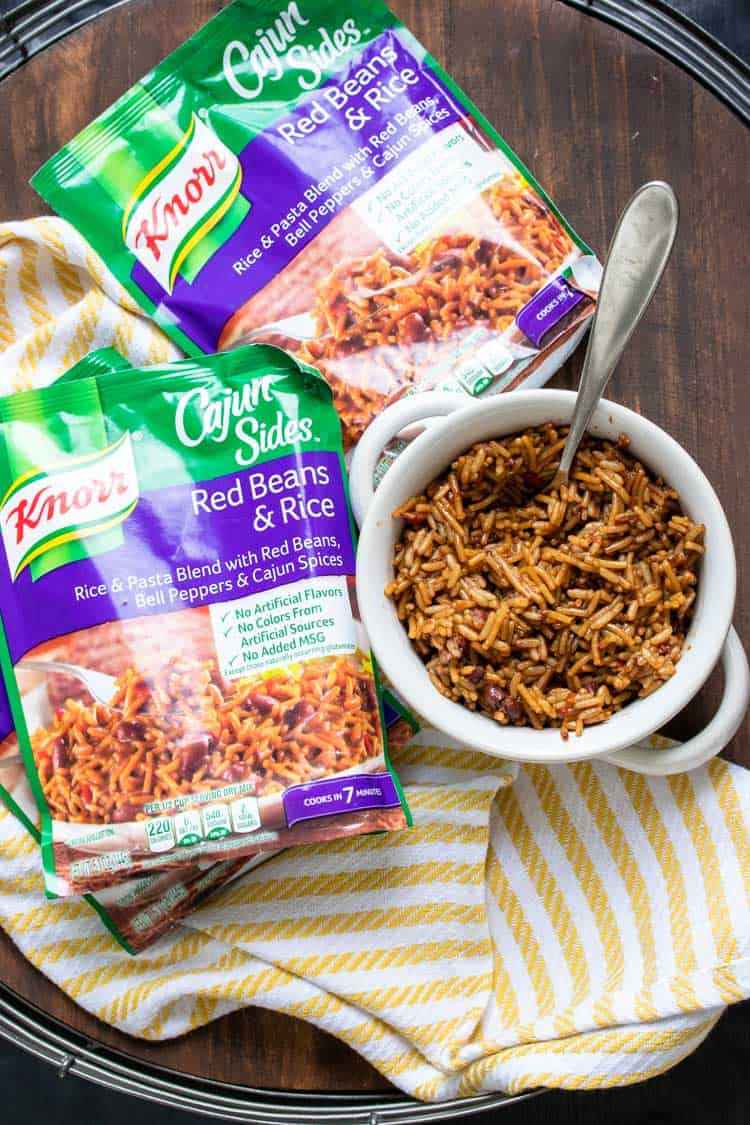 Bowl of cooked red beans and rice next to packs of ready mixes