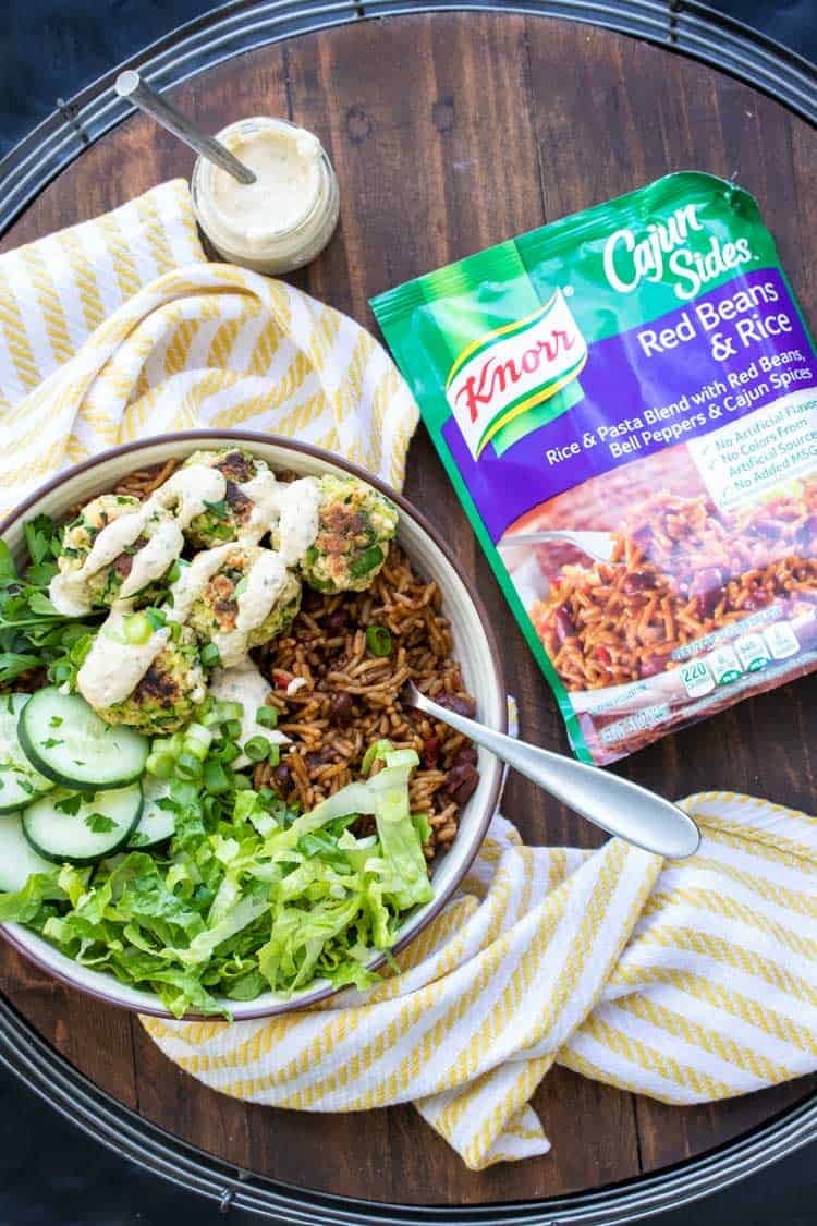 Bowl of zucchini fritters, rice and salad next to a ready rice pack