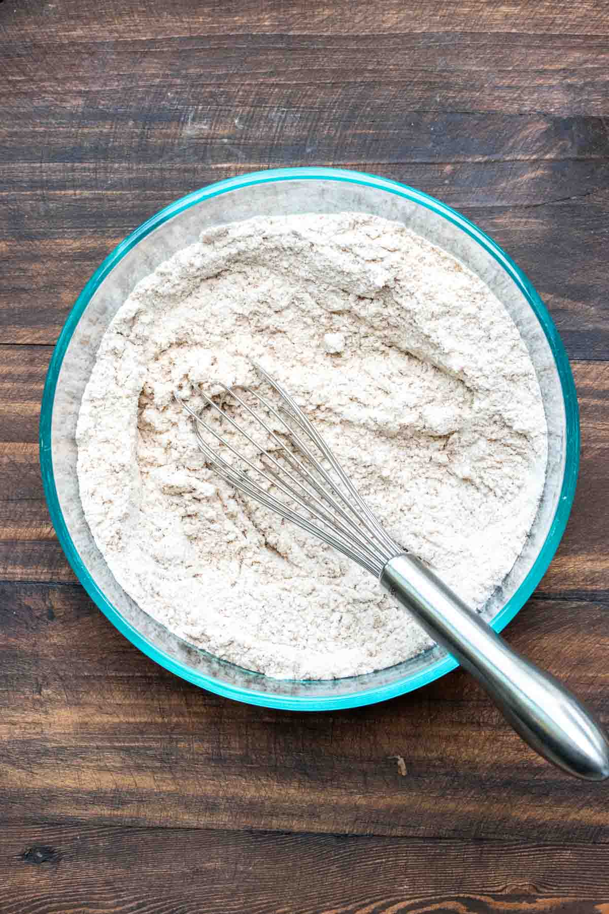 Top view of whisk mixing flour in a glass bowl