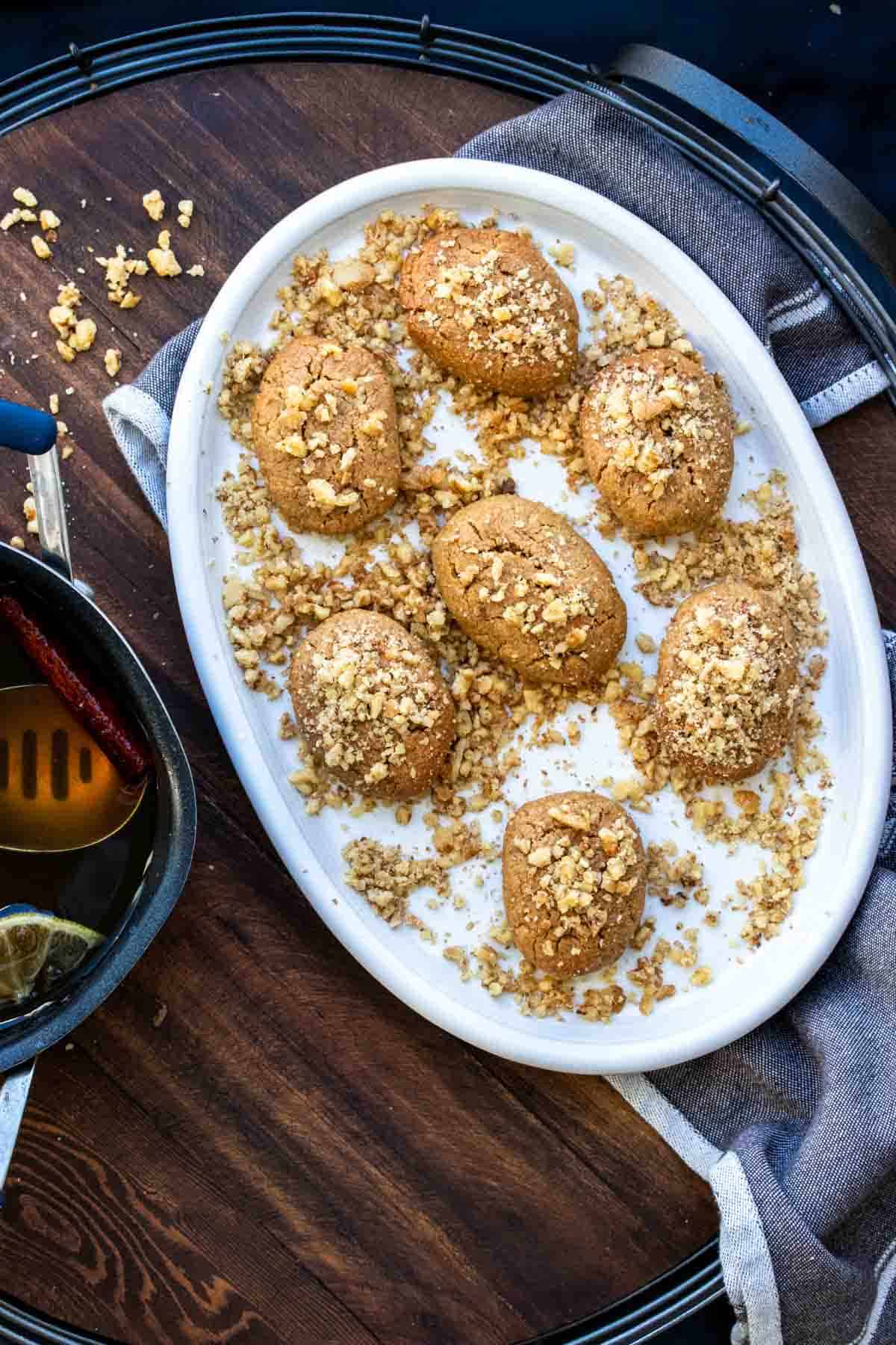 White platter of melomakarona cookies topped with walnuts