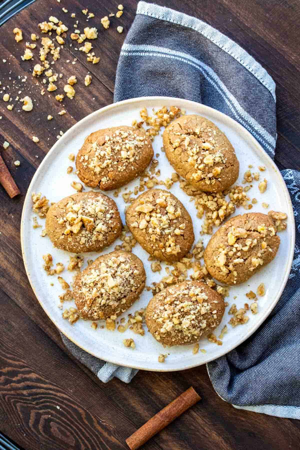 Round cream plate full of Greek melomakarona cookies with walnuts on top