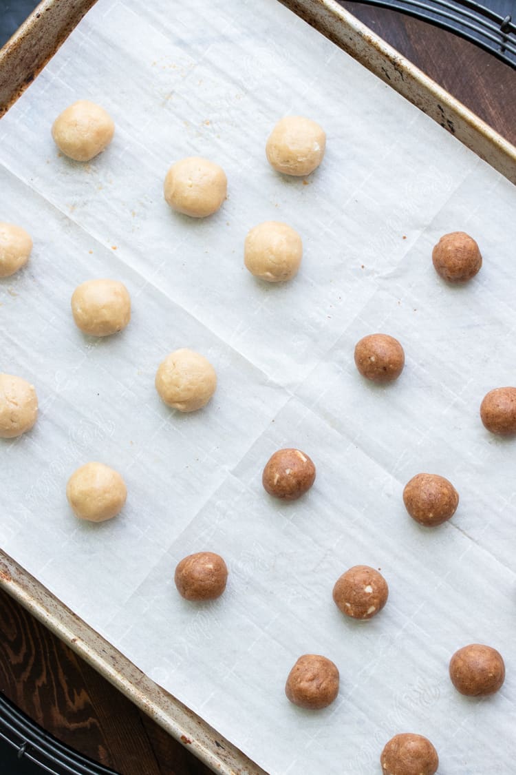 Balls of cookie dough on a parchment lined cookie sheet