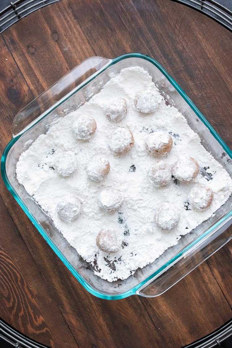 Glass baking dish with cookie balls covered in powdered sugar