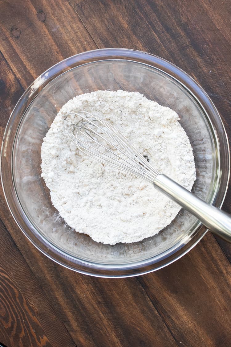 Glass bowl with flour being mixed with a whisk