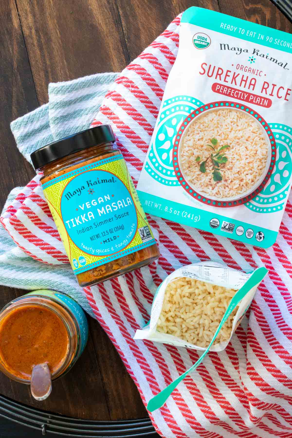 Jars of tikka masala sauce and packets of ready rice on striped towels